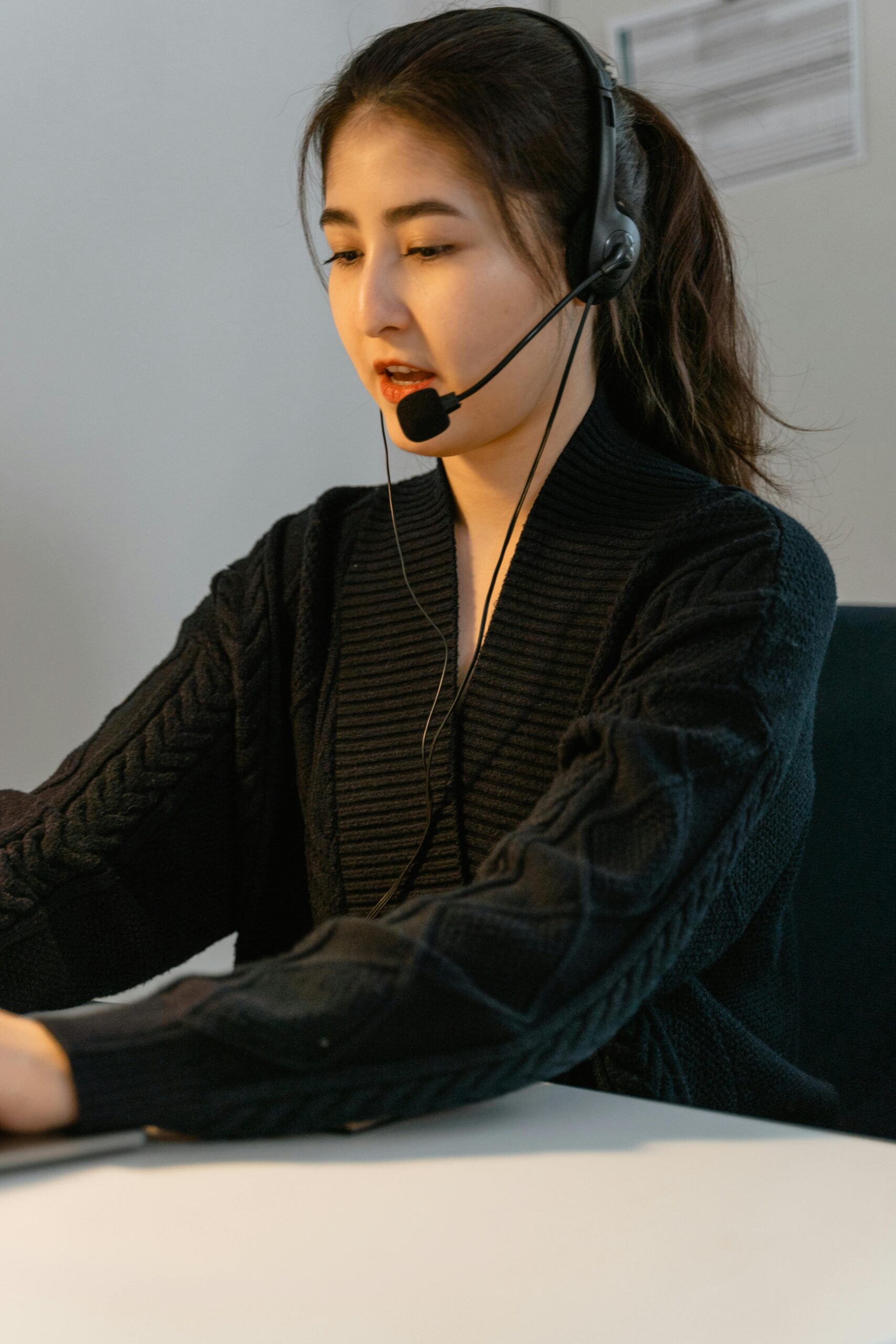 Professional Asian woman in customer support role wearing a headset, focusing on work.